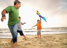 Father and Two Sons on Beach Flying Kite